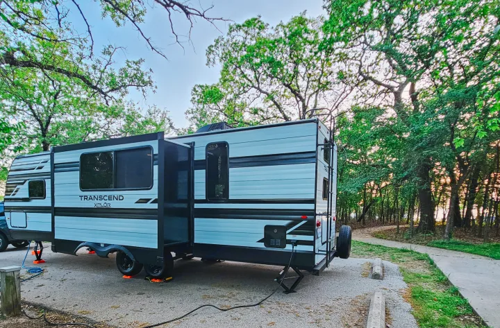 Transcend Xplor RV rental, perfectly leveled and set up at a scenic, treed campsite, ready for adventure.. Grand Design Transcend Xplor 2024