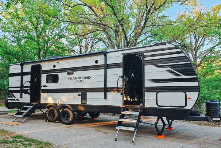 Enjoy your outdoor adventures with this RV rental! A Transcend XPLÖR travel trailer parked at a tree-filled campsite.. Grand Design Transcend Xplor 2024