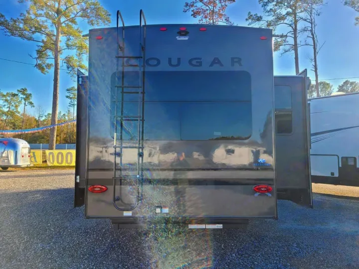Back of a dark Cougar fifth-wheel RV, featuring a ladder and large window. Perfect for your next rv rental adventure!. Keystone RV Cougar 2024