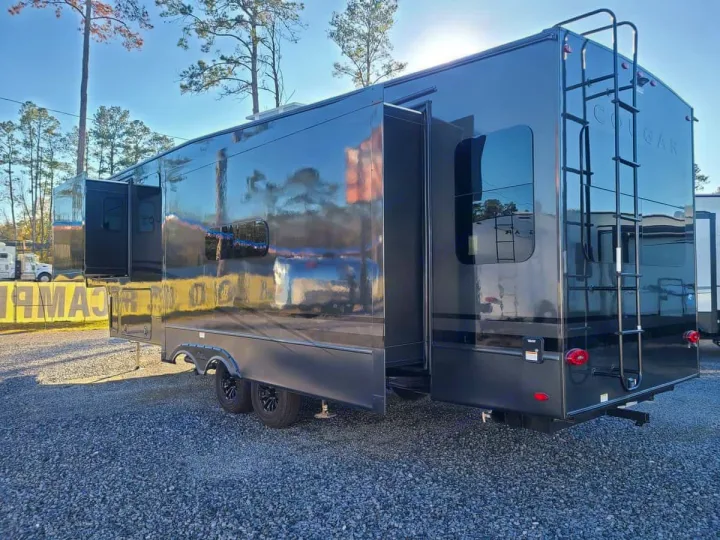 Sleek, reflective dark gray fifth-wheel RV with slide-out extended on gravel. Perfect for your next rv rental!. Keystone RV Cougar 2024