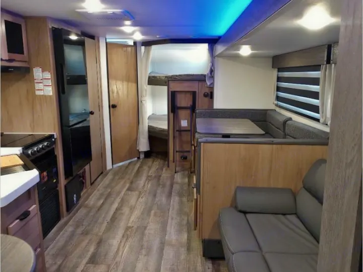Inside this modern RV rental: kitchen, dinette, sofa, and bunk beds. A well-lit, spacious travel trailer interior.. Forest River Cherokee Grey Wolf 2024
