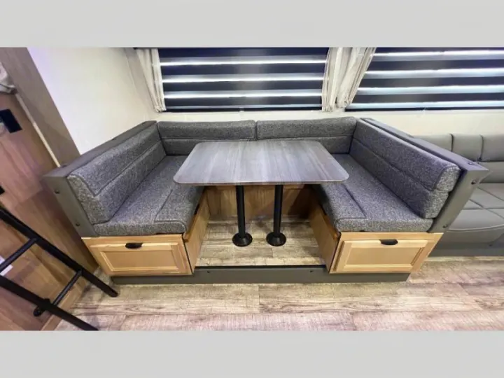 This RV rental features a modern U-shaped dinette with grey cushions, table, and under-seat storage.. Forest River Cherokee Grey Wolf 2024