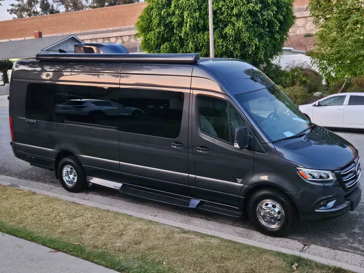 A dark gray Mercedes-Benz Sprinter camper van, available for rv rental, parked on a residential street.. Ultimate Toys SPRINTER 2025
