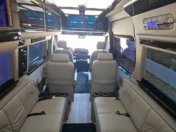 Spacious luxury RV rental interior with plush seating, entertainment screens, and wood floors for comfortable travel.. Ultimate Toys SPRINTER 2025