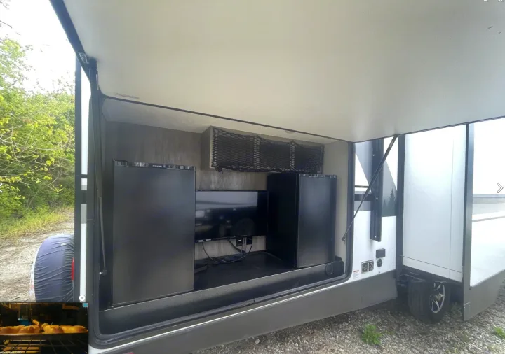 RV rental outdoor kitchen with TV, two fridges, and storage net, perfect for camping entertainment.. Forest River Vibe 2020