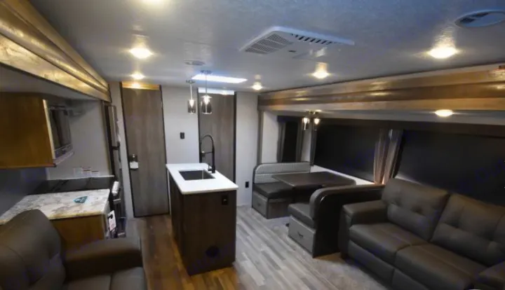 Spacious RV rental interior with a modern kitchen island, dining booth, and comfortable living area sofa.. Forest River Vibe 2020