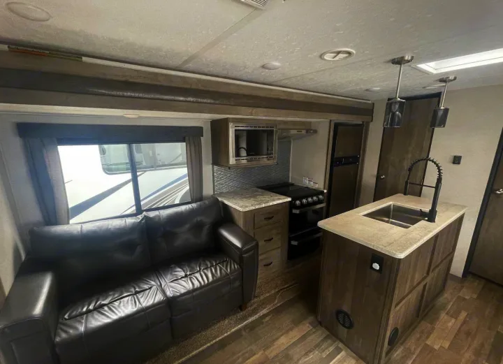 Spacious RV rental interior featuring a modern kitchen with island sink, stove, fridge, and comfortable sofa.. Forest River Vibe 2020