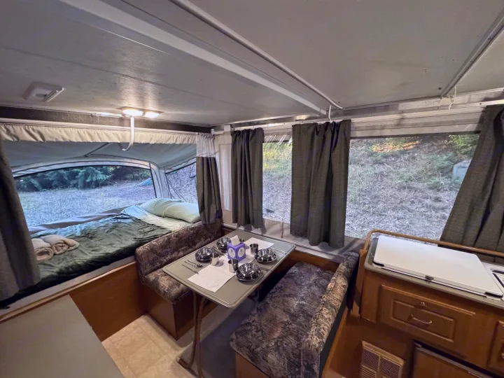 Cozy pop-up RV rental interior featuring a comfortable bed and a set dinette, perfect for your next camping trip.. Fleetwood Santa Fe 2004