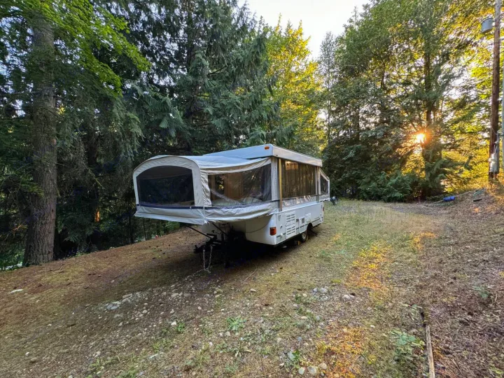 Experience nature with this RV rental! A pop-up camper nestled in a sunny forest clearing, ready for adventure.. Fleetwood Santa Fe 2004