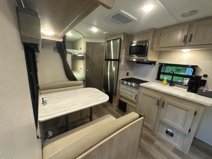 Spacious RV rental interior featuring a modern kitchen, comfortable dinette, and cozy bunk beds for family trips.. Coachmen 261BH 2024