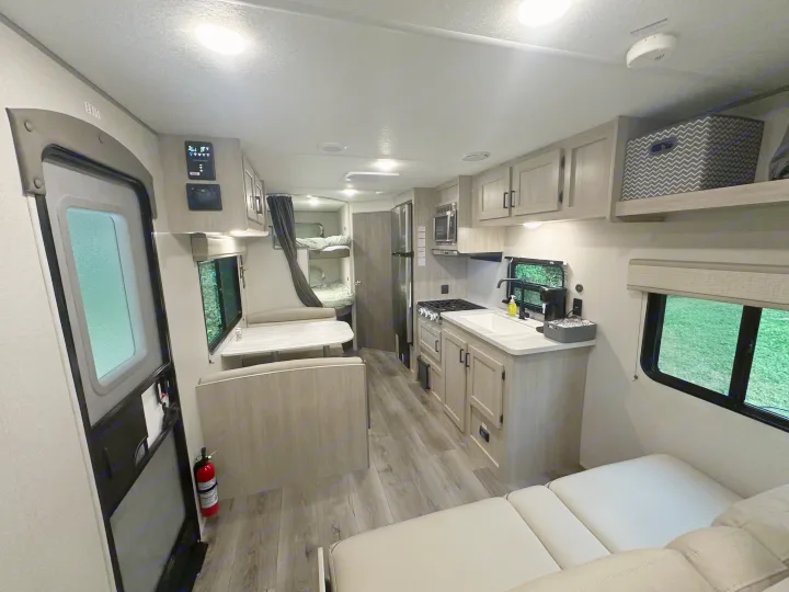 Spacious RV rental interior features a full kitchen, dining area, and bunk beds, offering comfort for your travels.. Coachmen 261BH 2024