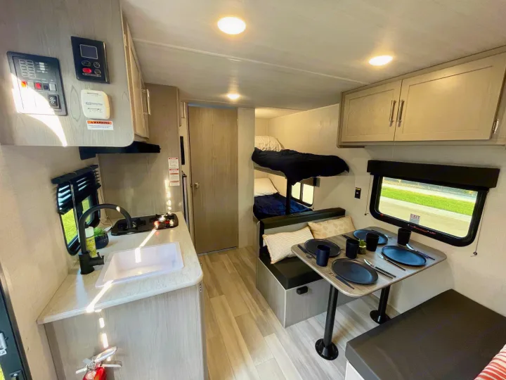 Spacious RV rental interior featuring a modern kitchen, cozy dinette, and bunk beds. Perfect for family adventures.. Keystone Springdale 1800BH 2024
