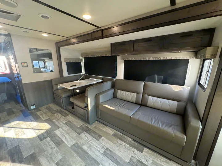 Spacious and clean RV rental interior showcasing a gray sofa, dining booth with marble-look table, and ample storage for travel.. Forest River Fr3 2021