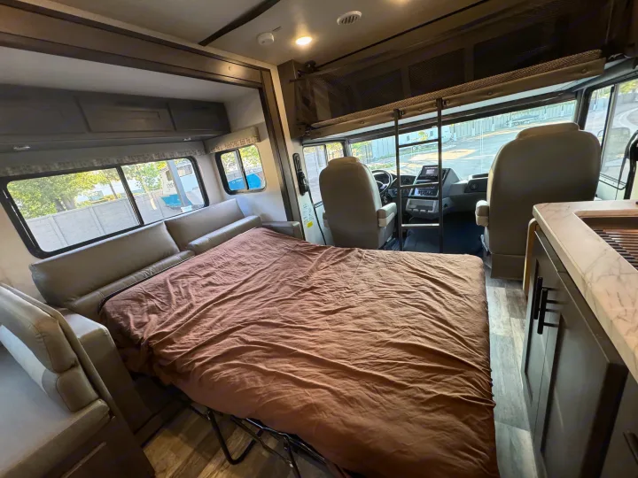 An RV rental's spacious interior with a cozy pull-out bed, driver's area, kitchenette, and overhead bunk.. Forest River Fr3 2021
