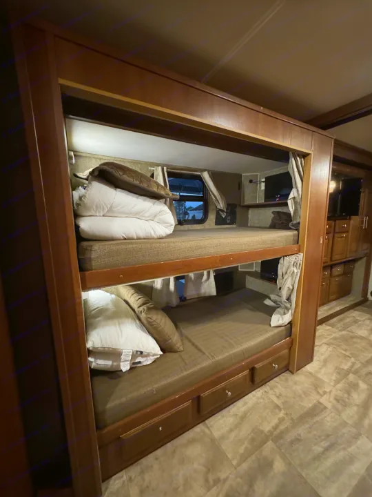 RV rental bunk beds: comfortable sleeping area with window, pillows, and built-in storage.. Forest River Georgetown 2018