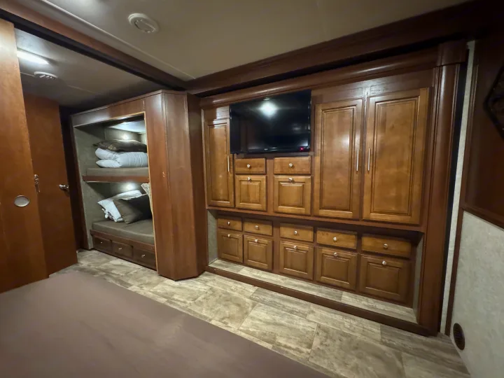 Explore this RV rental's clever interior design, showcasing cozy bunk beds, a mounted TV, and extensive built-in storage.. Forest River Georgetown 2018