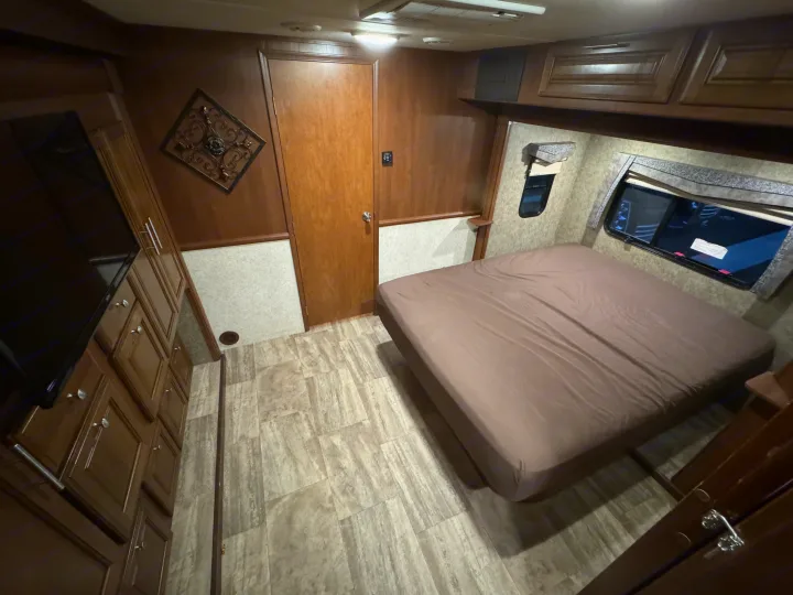 Cozy RV rental bedroom with wood-look flooring, comfortable bed, TV, and storage cabinets.. Forest River Georgetown 2018