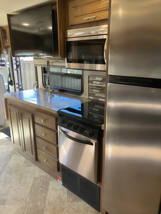 Step inside a modern RV rental kitchen. Features include stainless steel microwave, oven, fridge, and ample counter space with a sink.. Forest River GEORGETOWN GT5 2019