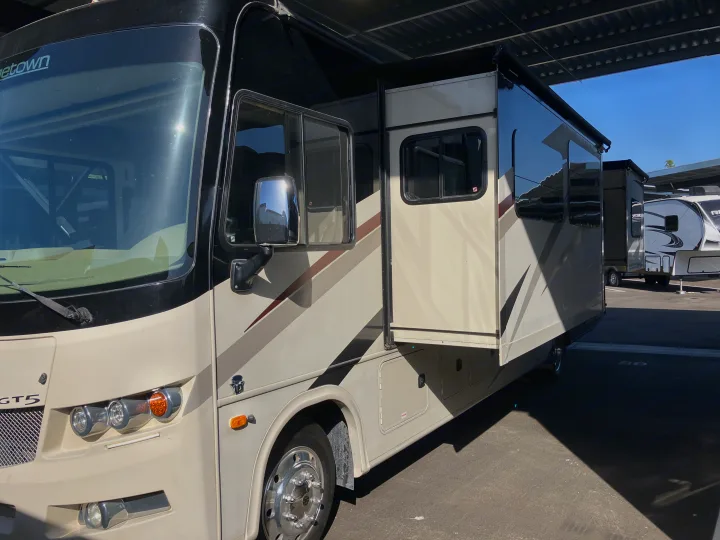 Cream and black Class A motorhome with extended slide-out, parked under shelter. Great for your next rv rental adventure.. Forest River GEORGETOWN GT5 2019