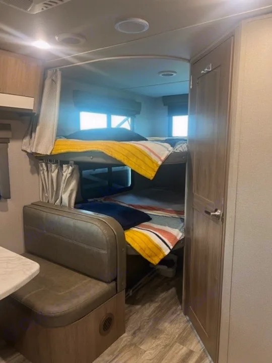 Cozy RV rental interior with bunk beds, dinette seating, and compact design for comfortable travel.. Grand Design Imagine XLS 2021