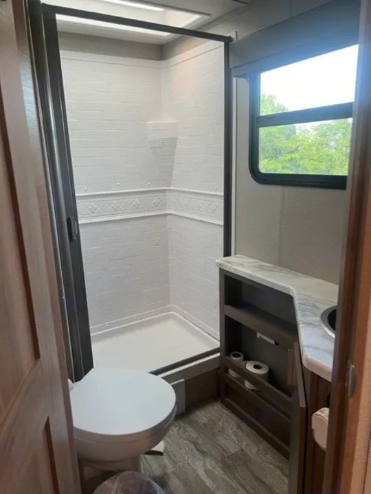 Experience comfort in your RV rental with this fully equipped compact bathroom, featuring a shower, toilet, and vanity.. Grand Design Imagine XLS 2021