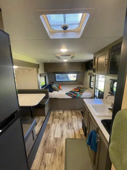 View inside an rv rental, showing the kitchen counter, dinette, and bedroom with a colorful blanket.. KZ SPORTSMEN CLASSIC 191BHK 2024
