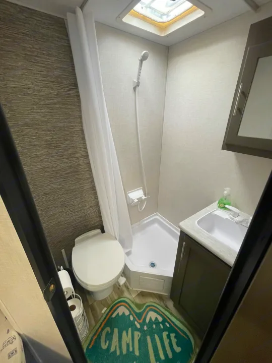 Experience comfort in this compact RV rental bathroom, featuring a shower, toilet, sink, and ceiling skylight.. KZ SPORTSMEN CLASSIC 191BHK 2024