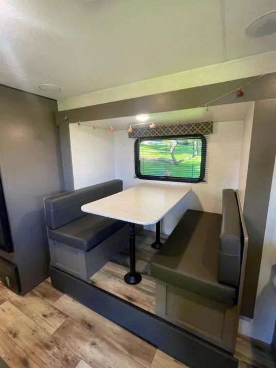 Cozy RV rental dinette featuring a table and comfortable booth seating, perfect for meals inside your travel trailer.. KZ SPORTSMEN CLASSIC 191BHK 2024