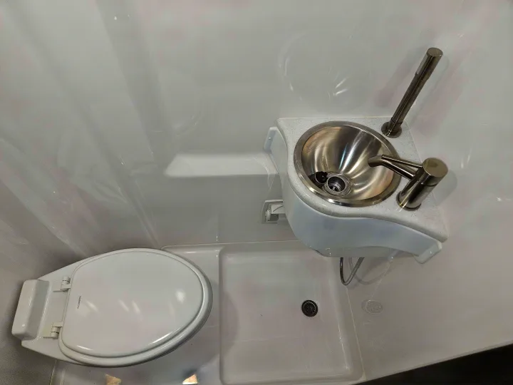 Compact RV rental wet bath with toilet, sink, and shower in one space, perfect for small living.. Ultimate Toys SPRINTER 2025