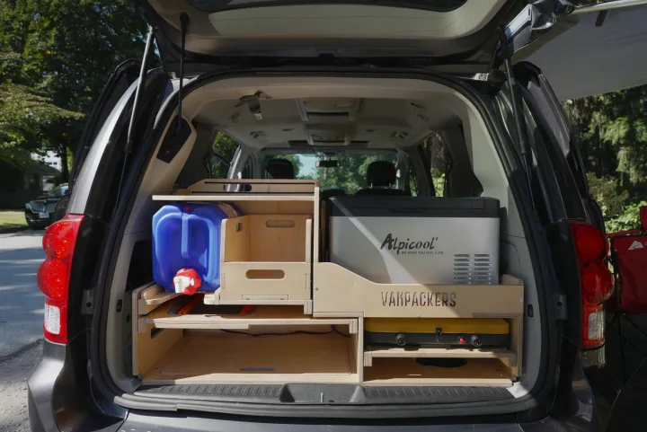 Minivan camper conversion features modular storage, water jug, Alpicool fridge, and stove. Perfect for an RV rental journey.. Dodge Caravan 2015