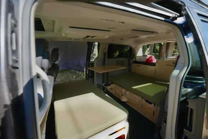 RV rental: Minivan camper interior with green padded beds, a modular table, and custom wooden storage. Ready for adventure.. Dodge Caravan 2015