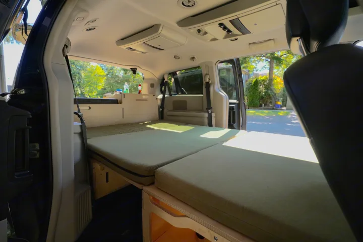 Transformed minivan interior, ready for your RV rental adventure! Features a cozy bed platform, storage, and open rear access.. Dodge Caravan 2015