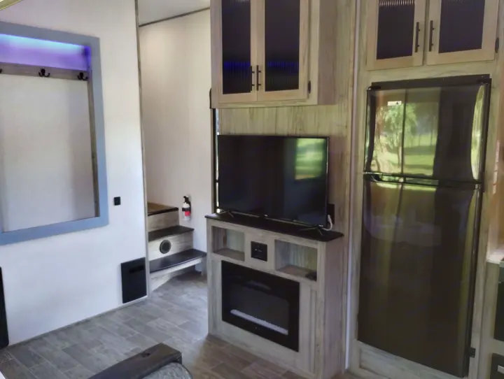 Explore this RV rental's cozy interior: TV, electric fireplace, full fridge, stairs, and coat rack with accent lighting.. Forest River Cherokee Arctic Wolf 2021