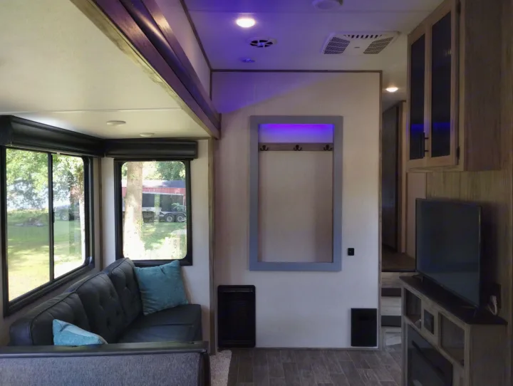 Modern RV rental living space with purple ambient lighting, comfy sofa, large windows & TV for your getaway.. Forest River Cherokee Arctic Wolf 2021