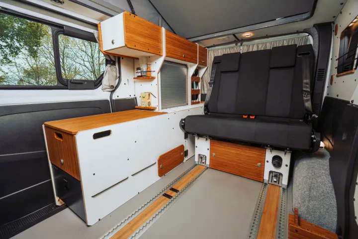 This RV rental interior features a modern camper van setup with bamboo accents, modular seating on floor rails, and ample storage.. Renault TRAFIC 2023