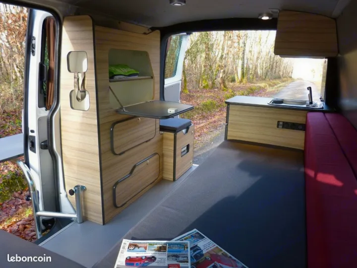 Explore this compact RV rental interior with a kitchen, folding table, and cozy bed, perfect for mobile adventures.. opel L'OTAGO (Caen) 2024