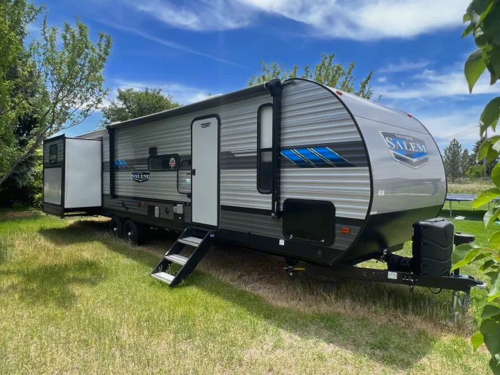 Spacious grey Forest River Salem travel trailer with extended slide-out, steps down, parked on green grass. Perfect for your next RV rental adventure!. Forest River Salem 2021