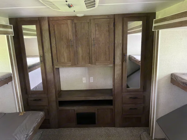 RV rental bunkhouse interior: wood-grained cabinets, mirrored wardrobes, and comfy bunk beds for a cozy stay.. Forest River Salem 2021