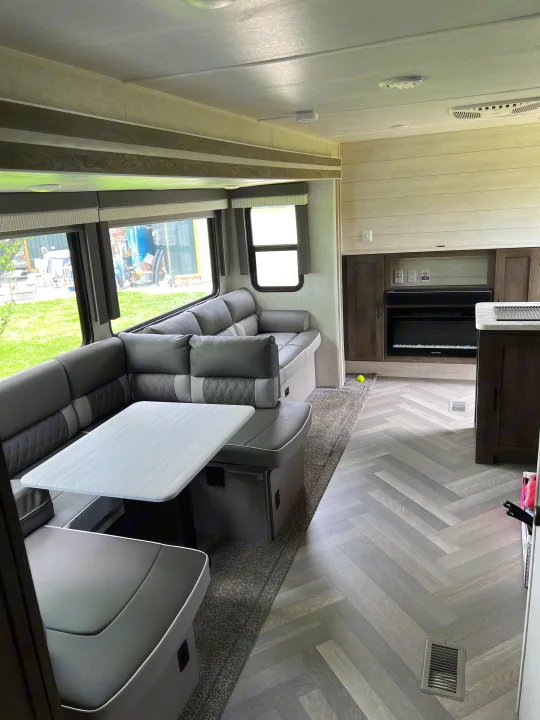 Spacious RV rental interior with grey dinette, large windows, herringbone floor, and fireplace, perfect for travel.. Forest River Salem 2021