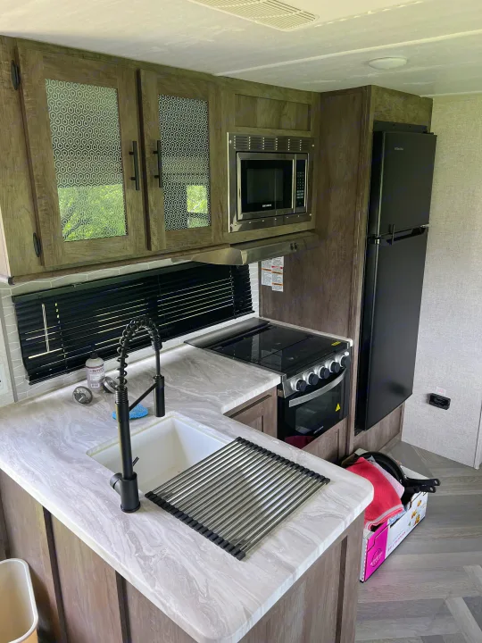 RV rental kitchen showcasing modern appliances: sink, microwave, stove, and refrigerator, in a compact space.. Forest River Salem 2021