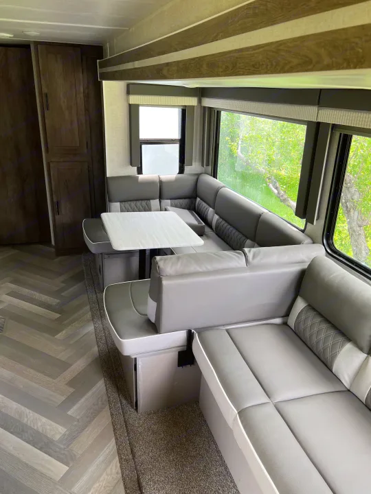 Clean, modern gray RV rental interior featuring a U-shaped dinette, large windows, and ample seating.. Forest River Salem 2021
