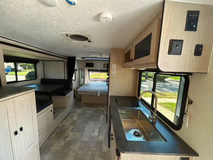 Discover a modern rv rental interior with a kitchenette, dinette, and bed, offering comfort for your journey.. Coachmen Apex Nano 2023