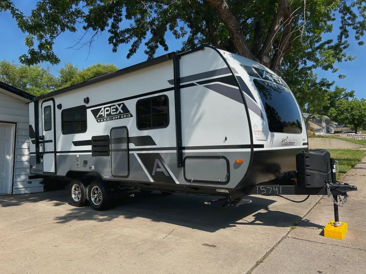 Bright white & gray travel trailer, perfect for an rv rental, parked on a sunny concrete driveway.. Coachmen Apex Nano 2023