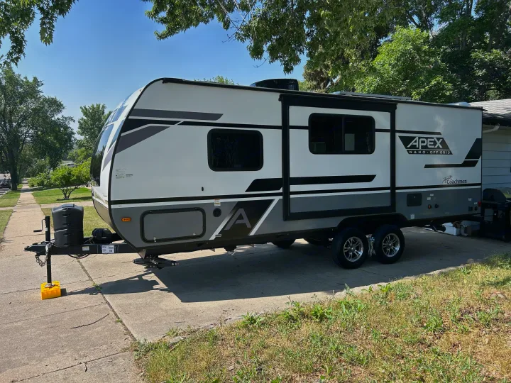 White & gray Apex Nano travel trailer, an ideal RV rental, parked on a sunny driveway, ready for off-grid adventures.. Coachmen Apex Nano 2023