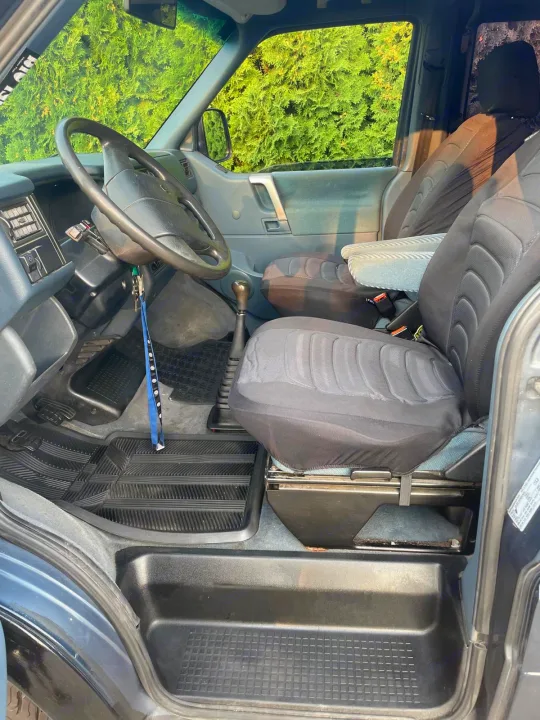 RV rental van's front interior, showing the driver's area, steering wheel, gear stick, and seats with covers.. Volkswagen eurovan 1996