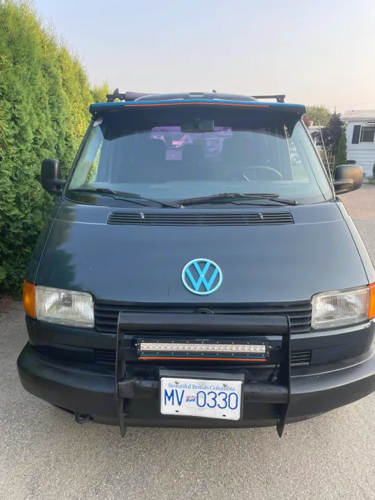 Dark Volkswagen camper van, ideal for rv rental, with a custom light blue emblem, LED bar, and British Columbia plate.. Volkswagen eurovan 1996