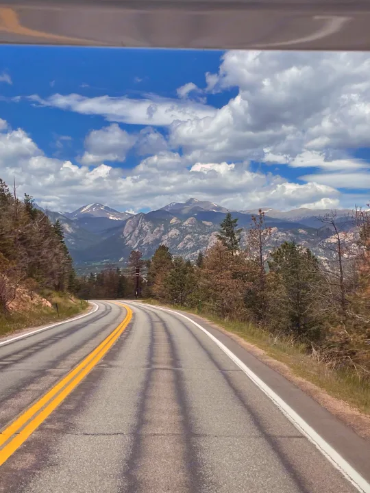 Hit the open road in your RV rental! Winding through mountains, past pine trees, with distant snow-capped peaks & a cloudy sky.. Thor Majestic 2019
