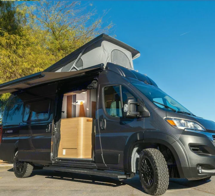 Modern dark gray camper van with pop-top roof, extended awning, and open door showing stylish interior, ideal for RV rental.. Noovo Pop 2024
