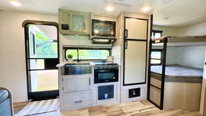Explore this cozy RV rental interior featuring a full kitchen, comfortable bunk beds, and scenic lake views.. Dutchmen Coleman Light 2023