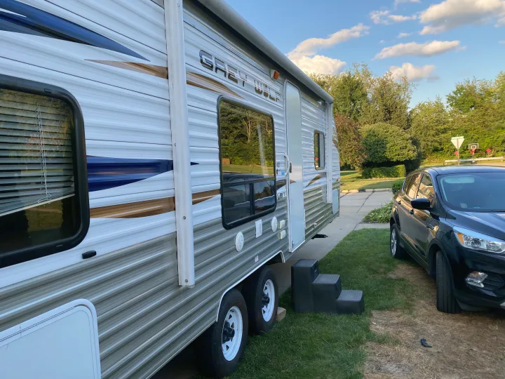 Explore with this Grey Wolf travel trailer, an ideal RV rental parked in a driveway next to an SUV.. Forest River Cherokee Grey Wolf 2012